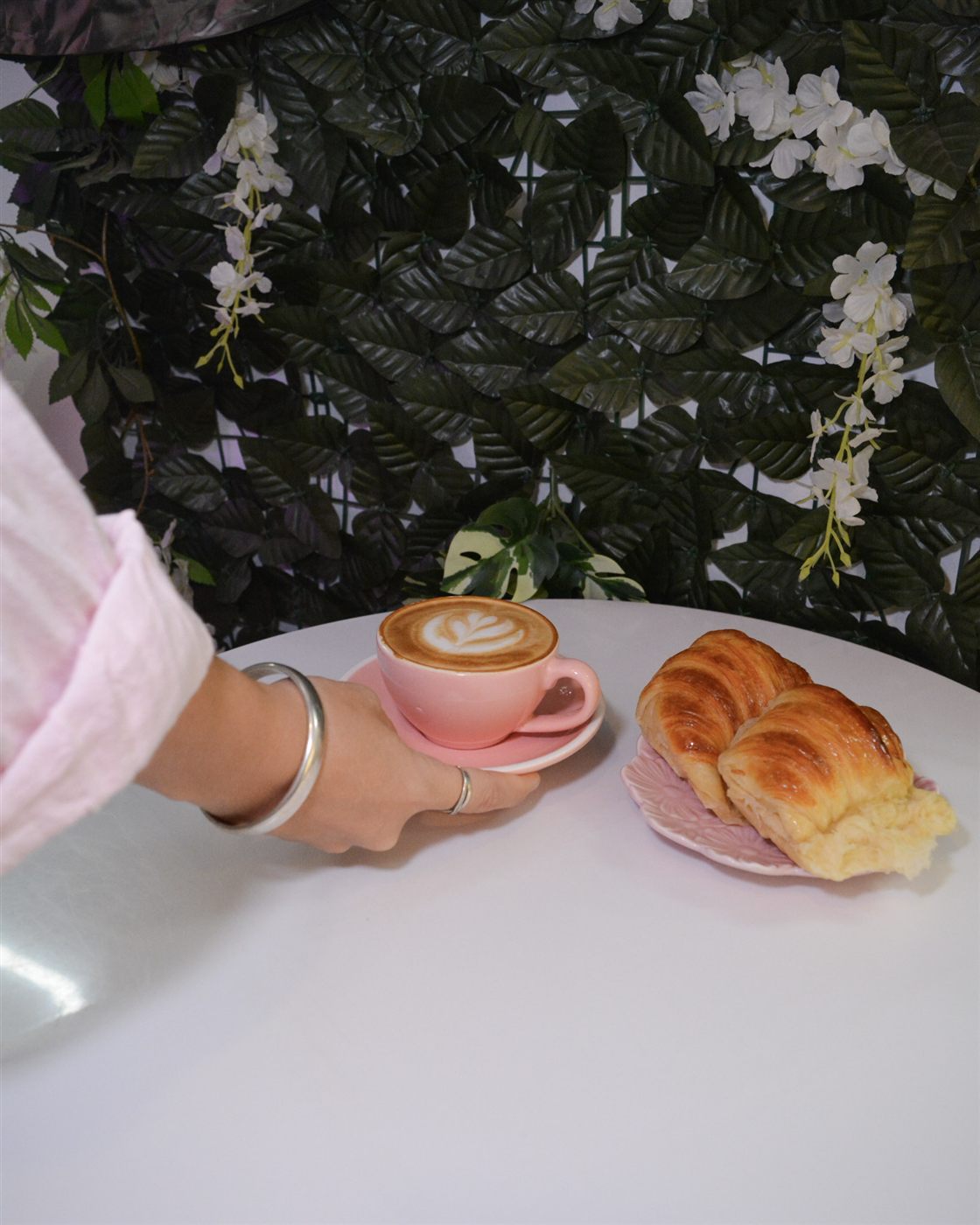 Café servido en taza rosa junto a croissants